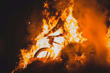 Totally crazy cyclist on a mountain bike riding through bonfire, sparks and flames whooshing past the biker in a real event. Biker dangerously playing with open fire.の写真素材