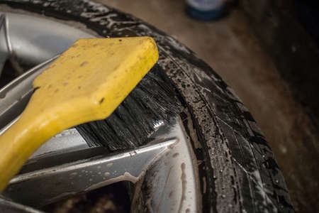 Cleaning of alloy or aluminium light wheels of a car with a yellow brush. Cleaning stubborn brake residue braking dust with cleaning solvent and a brush.の写真素材