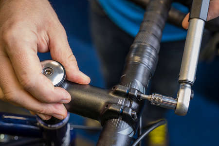 Tightening of a bicycle handlebar stem with the use of a small torque wrench. Proper way to tighten a bicycle handlebars. Bicycle service in a worshop.の写真素材