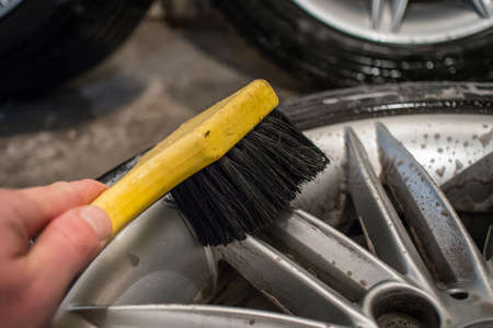 Cleaning of alloy or aluminium light wheels of a car with a yellow brush. Cleaning stubborn brake residue braking dust with cleaning solvent and a brush.の写真素材
