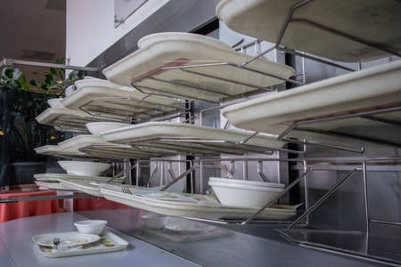 Deservicing conveyor belt for trays in a self service restaurant. Tray in a cafeteria on a belt which leads to cleaning facilities in the back of the restaurant.の写真素材