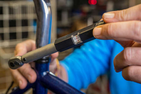 Tightening of a bicycle seat post with the use of a small torque wrench. Proper way to tighten a bicycle seatpost. Bicycle service in a worshop.の写真素材