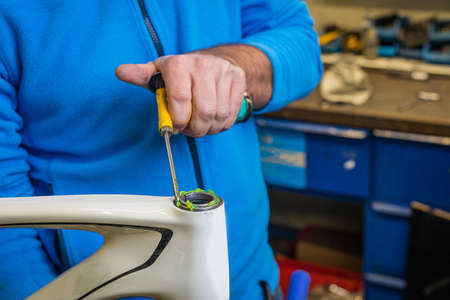 Greasing the upper part of a bicycle headset as a part of a bicycle maintenance. Man using a grease gun to lube the upper part of a bicycle headset.の写真素材
