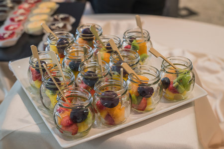 An assortiment of dessert fruit on a white plate at a banquet or a party. Catering with fruit in glass jars.の写真素材