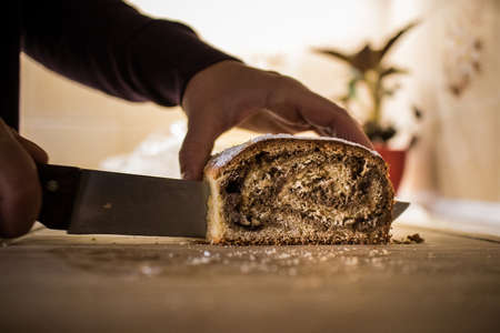 A person cutting a traditional slovenian dessert called potica with a knife on a kitchen desk. Knife visible on the bottom of the cutting stroke.の写真素材