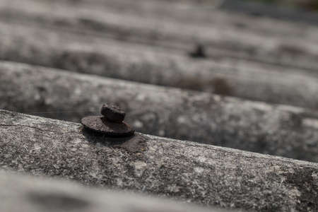 Old roofing tiles made of asbestos and cement. Dangerous and unhealthy roofing, visible old and rusty screw for fixing the tiles.の写真素材