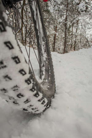 Detail of a mountain bike tire tread filled with snow, on a snowy surface. Extreme mountain bike ride in winter time with snow.の写真素材