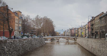 River through the centre of Sarajevo, Bosnia on a cold cloudy winter day. Visible the bridge and old houses next to it.の写真素材