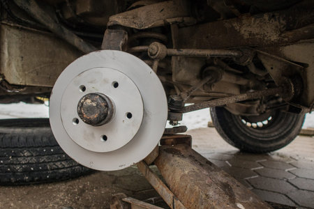 New shiny gray or silver brake disc freshly installed on an old car. Visible undercarriage of a car...