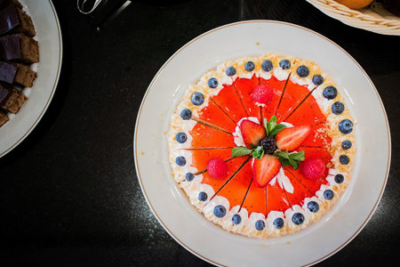 Strawberry cake with white topping and blueberries on the edge. View of a cake from above.