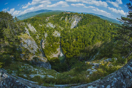 Overview of Skocjan caves way below the village of Skocjan on a picturesque summer day. Fish eye or wide angle view of Skocjan caves.の写真素材