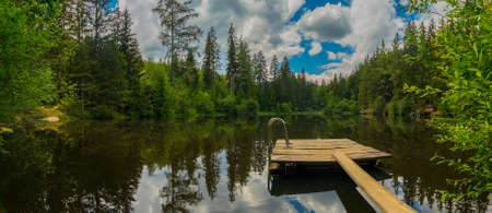 View of Podolerteich a beautiful alpine lake in the middle of the forest with visible wooden pier.の写真素材