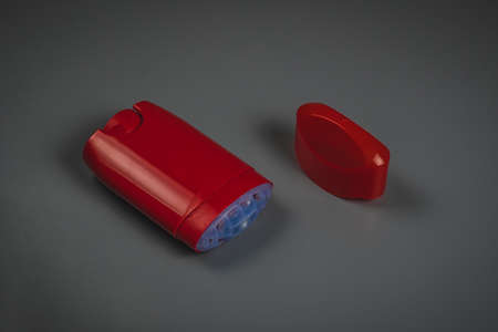 Empty red deodorant stick with open top on a gray background. Visible empty deodorant stick with exposed mesh containing the material which is practically non existentの写真素材