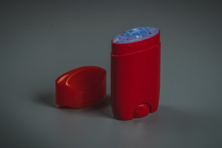 Empty red deodorant stick with open top on a gray background. Visible empty deodorant stick with...