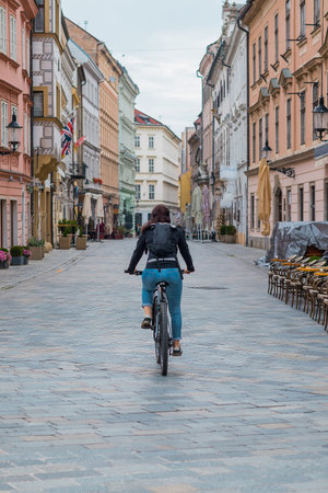 Streets of Bratislava, Slovakia, on a dull day, a female biker is visible riding her bike away from...