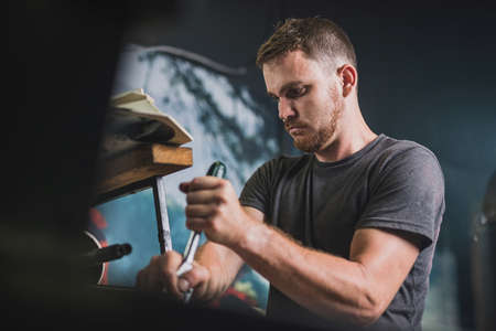 Professional serviceman is repairing an outboard engine using a spanner to untighten screw. Man fixing an outboard in a fancy workshopの写真素材