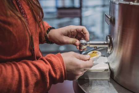 Hands of a woman seen using an industrial grade dispensers for sauce.