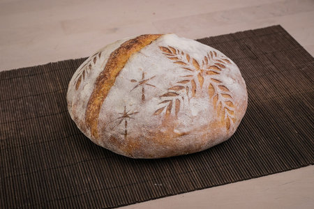 Home made traditional loaf of bread in slovenia with carved images of leaves and grain wheat on the...