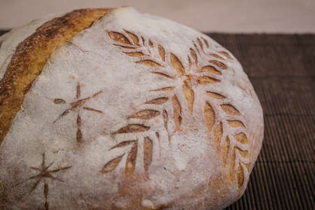 Home made traditional loaf of bread in slovenia with detail of carved images of leaves and grain wheat on the crust. Festive bread with ornamental decorations.の写真素材