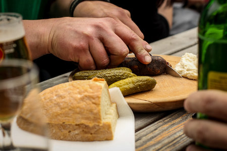 A person cutting a home made sausage or salami in the hills. Closeup of hands with the knife.の写真素材