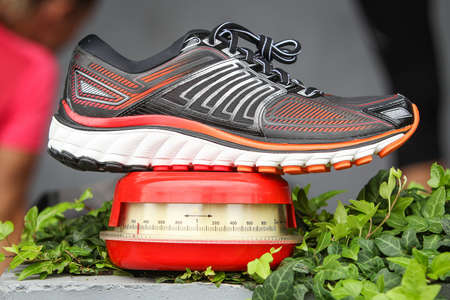 Side view of a running shoe on a scale. Weighing sneakers.の写真素材