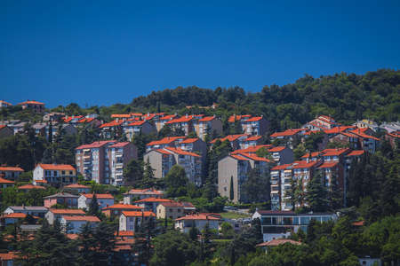 Small city blocks on a hill covered with trees at Semedela close to Koper, Slovenia. Houses and condominiums on a small hill during a sunny day.の写真素材
