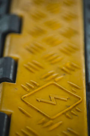 Black and yellow plastic cable protector on the ground. Floor cable protector with plastic cover. Cable saver on an event in high visibility colors.の写真素材