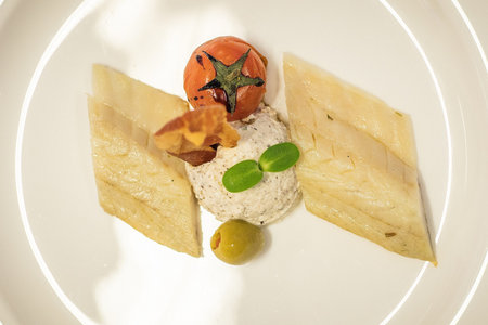 Fancy food on a plate. Slow food dinner menu consisting of fish, olive, prosciutto, parsley, cheese,...
