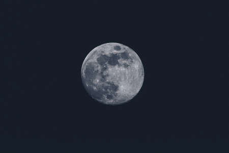 Full moon over dark background sky. Closeup of a moon on the sky, round shape of a moon on black sky.の写真素材