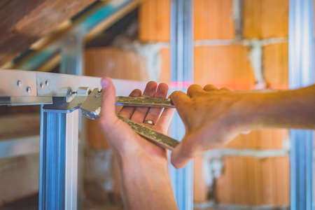 Drywall plaster stud crimpers in action. A person holding and using stud crimping tool in hand while building a metal drywall construction in a house during renovationの写真素材