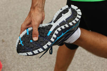 A man is checking the tread on his running shoe. Man standing on one leg and with other leg bent to expose the thread on his running shoe or sneaker.の写真素材
