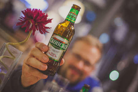 SKOPJE, MACEDONIA, 8. NOVEMBER 2015: A man holding a bottle of Skopsko beer next t a flower. Drinking in Skopje.のeditorial素材