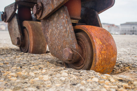 Old and rusty industrial wheels of a sliding door sunk into the asphalt ground due to the lack of usage,. Cart wheels sunk into the ground due to weight.の写真素材