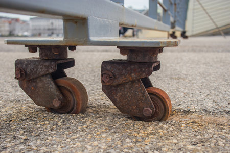 Old and rusty industrial wheels of a sliding door sunk into the asphalt ground due to the lack of usage,. Cart wheels sunk into the ground due to weight.の写真素材