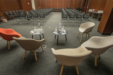 Empty chairs for a conference round table in an empty conference hall. A hall prepared to take the visitors and speakers of a conference.の写真素材