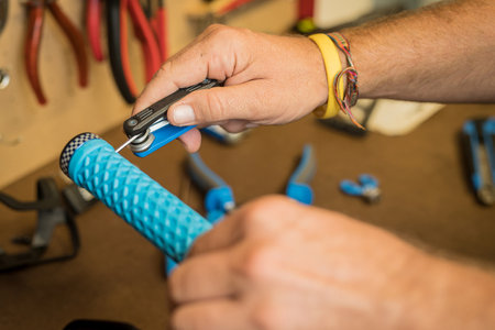 Lock on bicycle grips waiting to be installed on handlebars. Hands of a person seen holding a multi tool and fixing bicycle grips.の写真素材