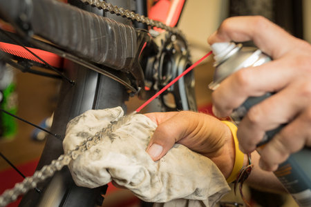 Degreasing the chain of a bicycle using an aerosol spray with degreasing agent. Man holding a spray to clean the chain.の写真素材