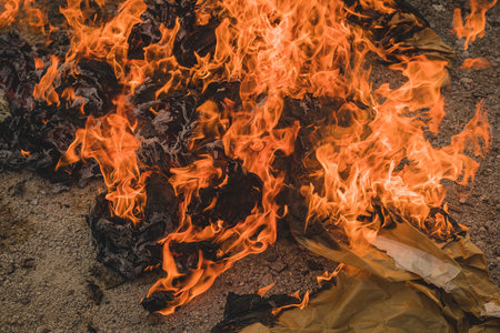 Burning a fire out of paper in an open space. Burning paper waste in residental or industrial environment. Pollution with burning paper.の写真素材