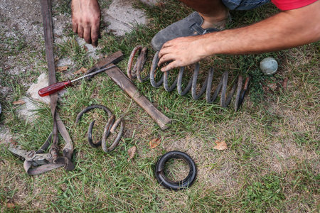 Amateur car mechanic is lowering a car with cutting the springs. Cheap lowering of a car. Different tools visible on the ground.の写真素材
