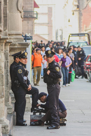 MEXICO CITY, MEXICO, 21.1.2012: A group of police officers are getting their shoes cleaned by a...