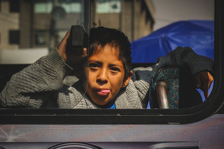 MEXICO CITY, MEXICO, 21.1.2012: Mexican kid showing his toungue from a local bus in the city. Nosy kid showing his tongueのeditorial素材