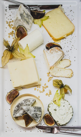 A fairly rich assortment of different cheese on a platter in a restaurant.の写真素材