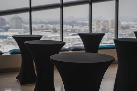 Multitude of empty elegant black standing tables for lunch reception with a nice view behind over the city blocks.の写真素材