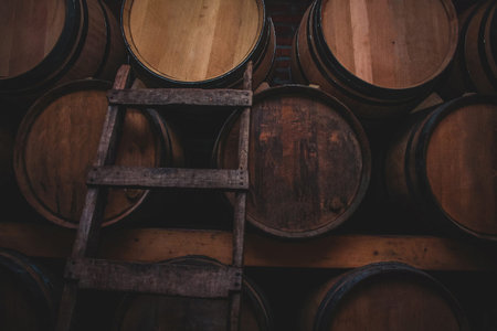 Three stacks of wooden wine barrels in a wine cellar. Ladder to climb towards the upper barrels is seen.の写真素材