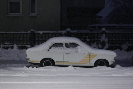 An old vintage car under a thick layer of snow in the night.の写真素材