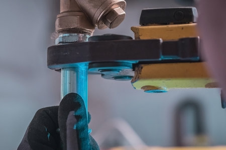 Plumber using pipe fastener or battery press tool to crimp heating or warm water pipes together. House renovation.の写真素材