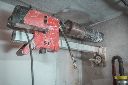 Machine for drilling holes in hthe concrete wall. Red professional drill for making holes in the walls. Back view with diamant drill mounted.の写真素材