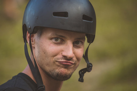 Young caucasian male model is wearing a black bicycle or skate helmet and making a duck face. Cool guy wearing a helmet outdoorsの写真素材