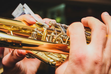 Detail of hands of a man playing on the trumpet while holding a euro note money bill. Concept of earning money with playing music with a band on different ocasionsの写真素材