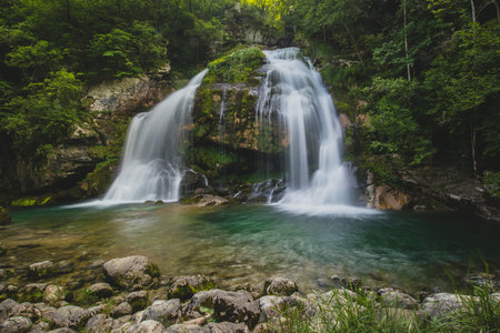 Long exposure of magical looking Virje waterfall in Slovenia, close to bovec. Dreamy and enchanting water falling down the cliff above the small alpine lake.の写真素材